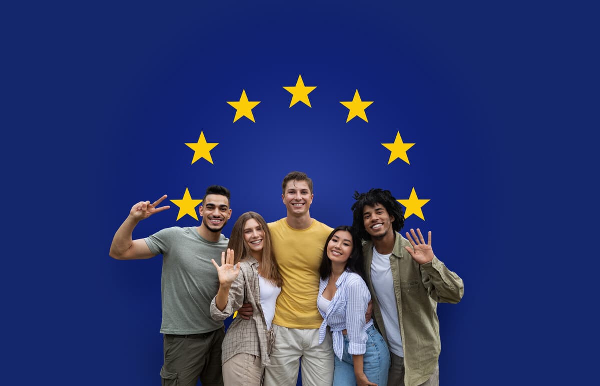 Pessoas de diferentes raças posando em frente à bandeira da União Europeia. Benefícios da cidadania europeia: descubra as vantagens de ter um passaporte da União Europeia