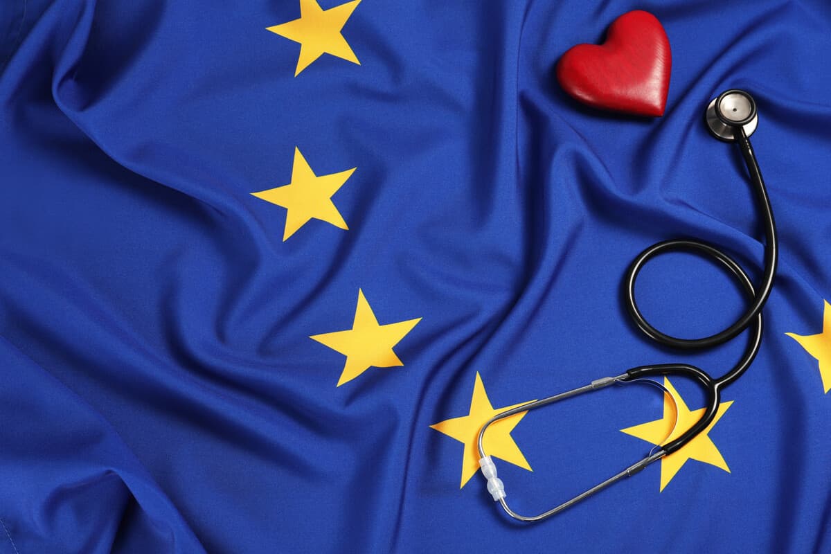 Bandeira da União Europeia com um estetoscópio médico e um pequeno coração vermelho. Benefícios da cidadania europeia: descubra as vantagens de ter um passaporte da União Europeia