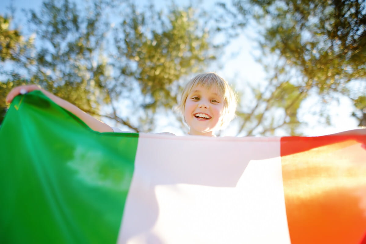 Criança loira com bandeira italiana. Cidadania italiana: Senado aprova prazo para menores até 2029