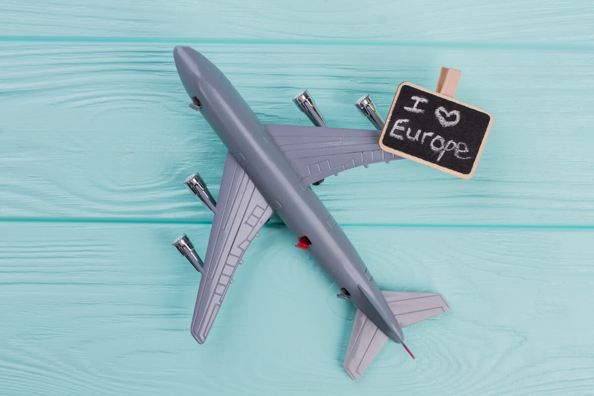 Foto de um avião de brinquedo cinza sob uma estrutura amadeirada de cor verde-água com uma plaquinha escrita "I love Europe" em cima da asa direita. Benefícios da cidadania europeia: descubra as vantagens de ter um passaporte da União Europeia