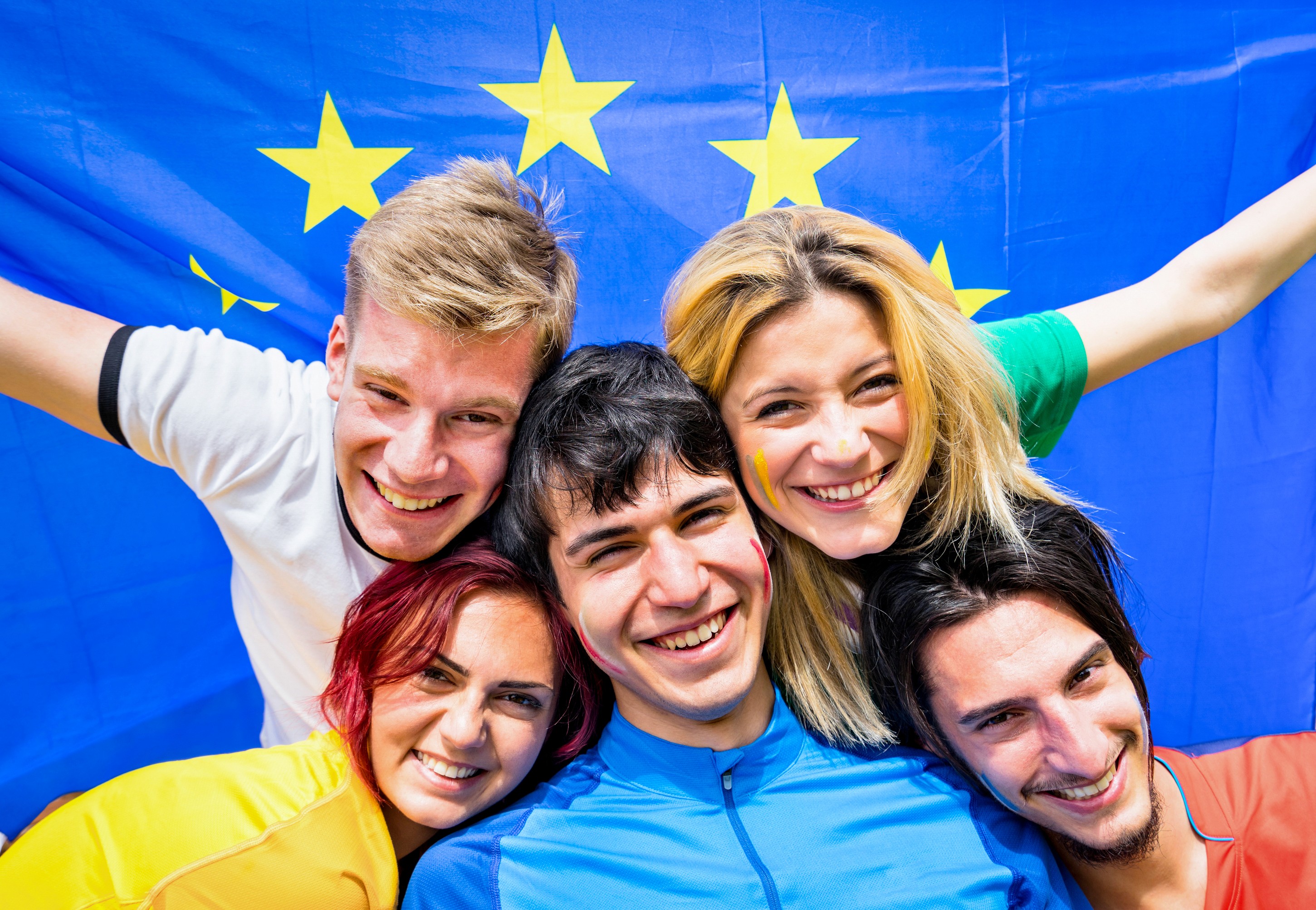 Jovens felizes em frente à bandeira da União Europeia