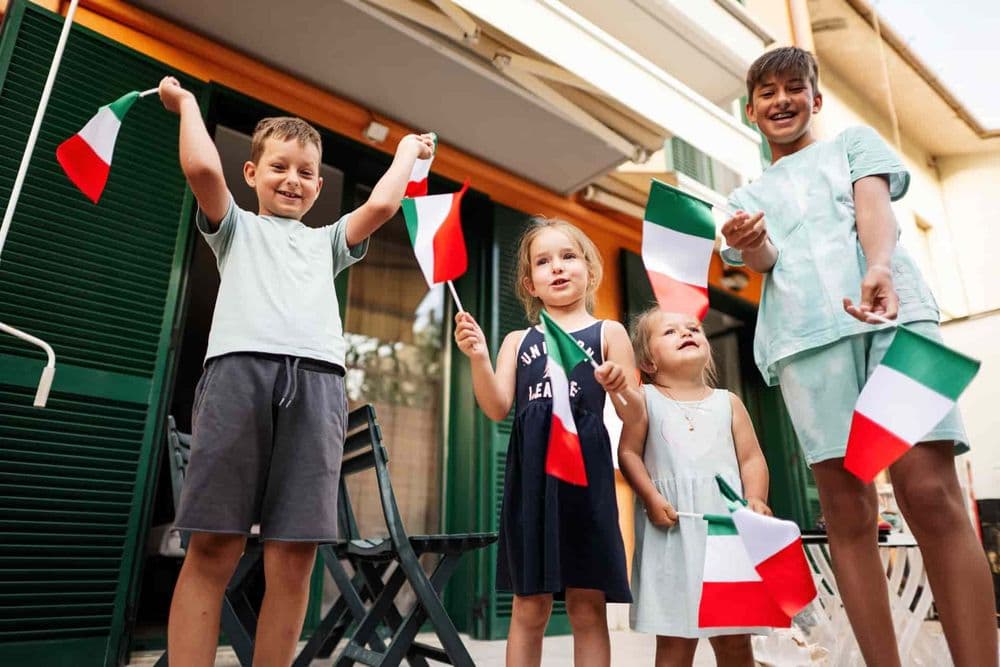 Crianças felizes segurando bandeirolas da Itália. Cidadania italiana: Senado aprova prazo para menores até 2029