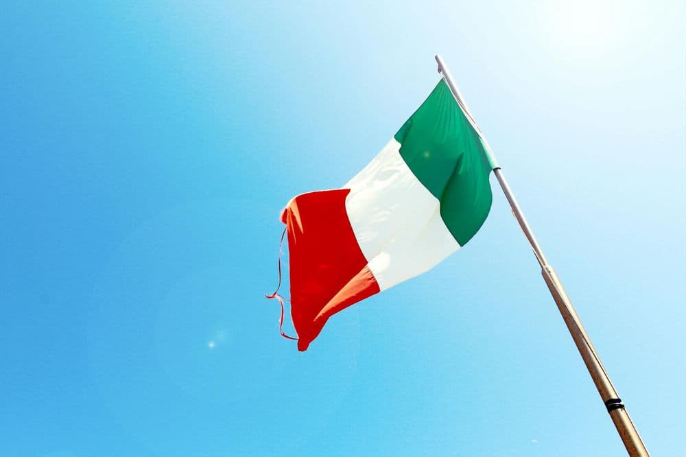 Foto da bandeira italiana estendida diante de um céu azul