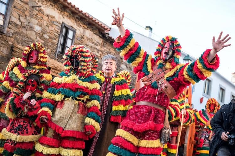 Homens fantasiados de Caretos, trajando vestes vermelhas, com algumas listras amarelas e verdes, em franjas e com capuz. Também carregam uma máscara a