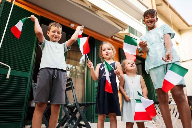 Crianças felizes segurando bandeirolas da Itália. Cidadania italiana: Senado aprova prazo para menores até 2029